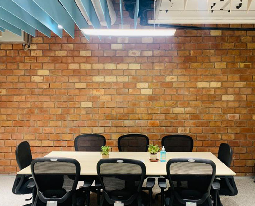 A small gathering of young professionals in a modern classroom with wall-to-wall sunlit windows 