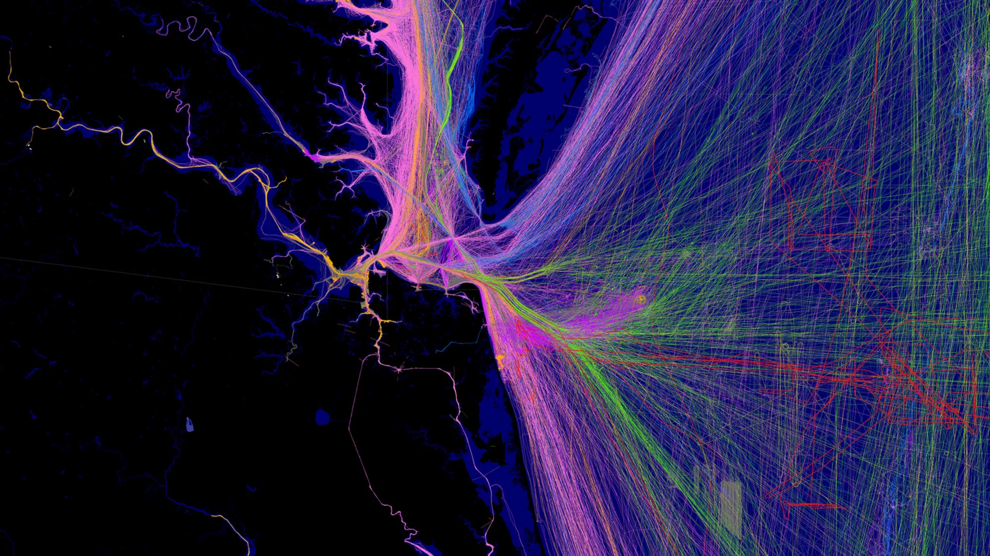 Real-time data visualization of transportation or movement patterns, with neon lines in purple, pink, and green spreading across a dark map, showing high-traffic pathways.