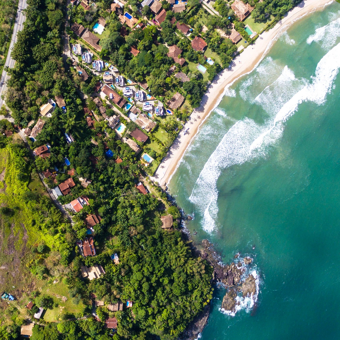 Aerial image of buildings, homes, and green trees along a coastline and blue ocean