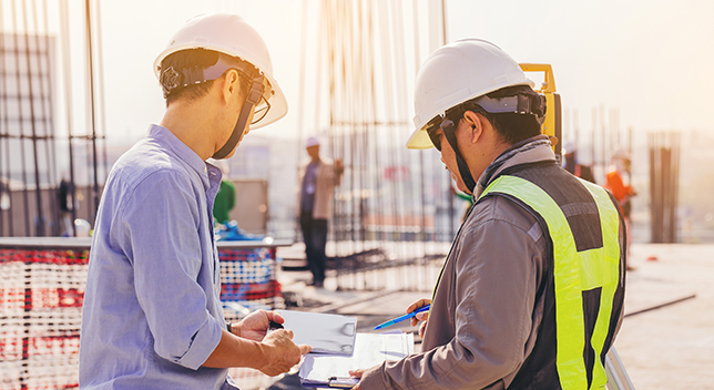 Two people on a construction site wearing hard hats