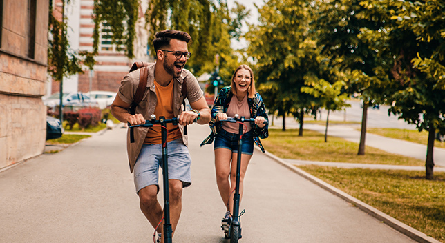 Two people riding scooters