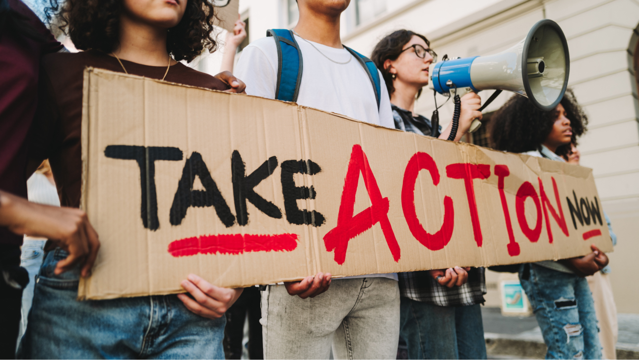 People holding a sign that says “Take Action Now”