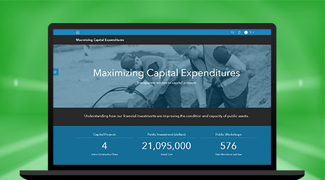 A laptop computer showing a webpage called “Maximizing Capital Expenditures” with a real-time information section about population, community projects, and more
