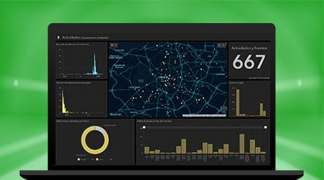 A laptop computer showing a dashboard with circle graphs, bar graphs, and numbers, and a map of illuminated locations