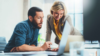 Two people at a desk sharing a computer