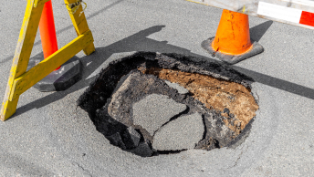 A sinkhole in a street blocked off by safety cones